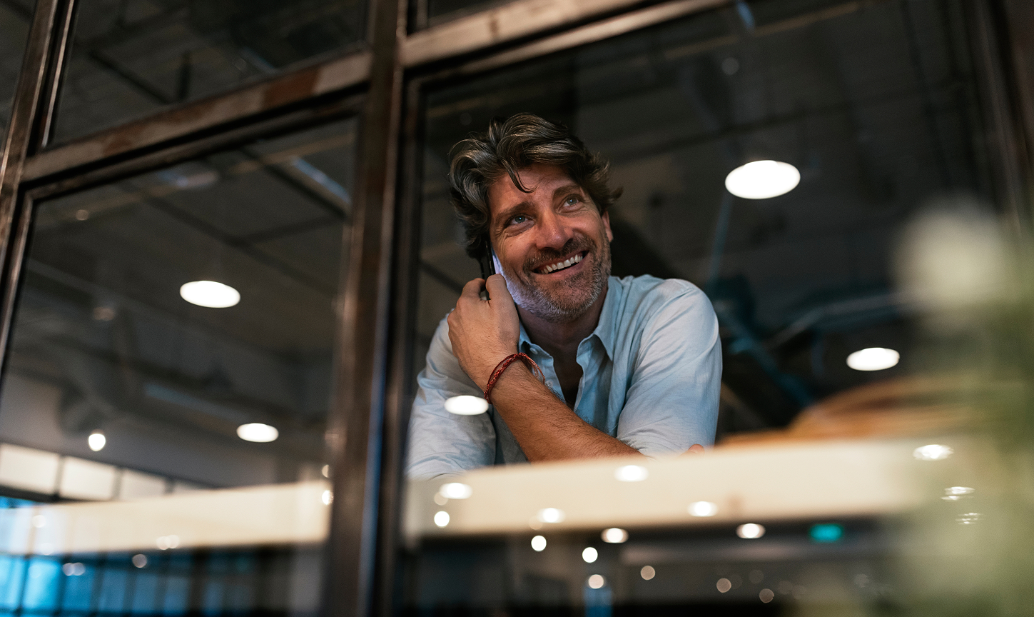 business man on phone smiling looking through window